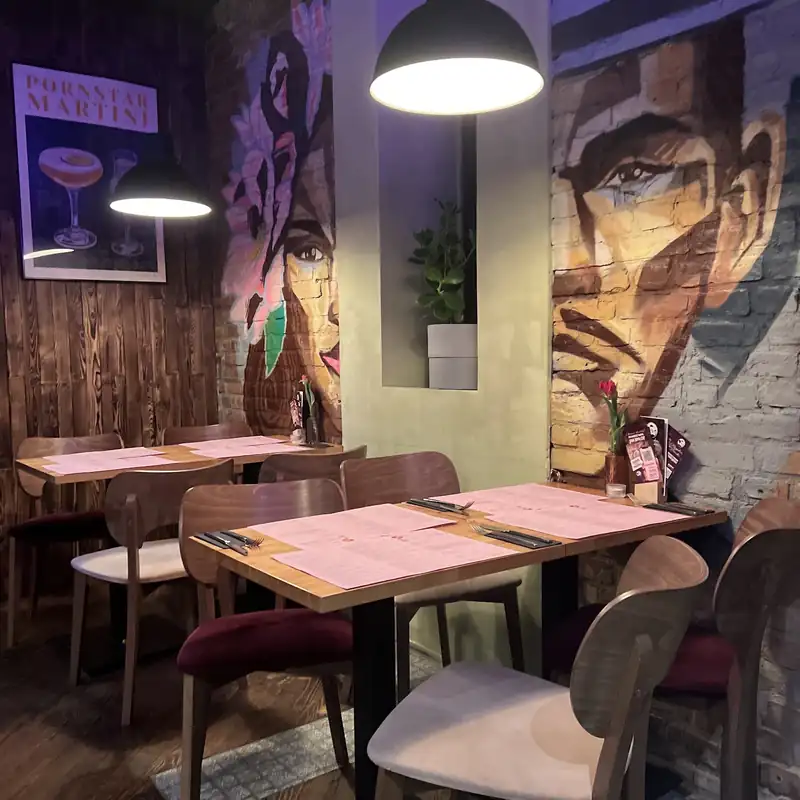 Sala z muralem na ścianie, lampami i drewnianymi stolikami